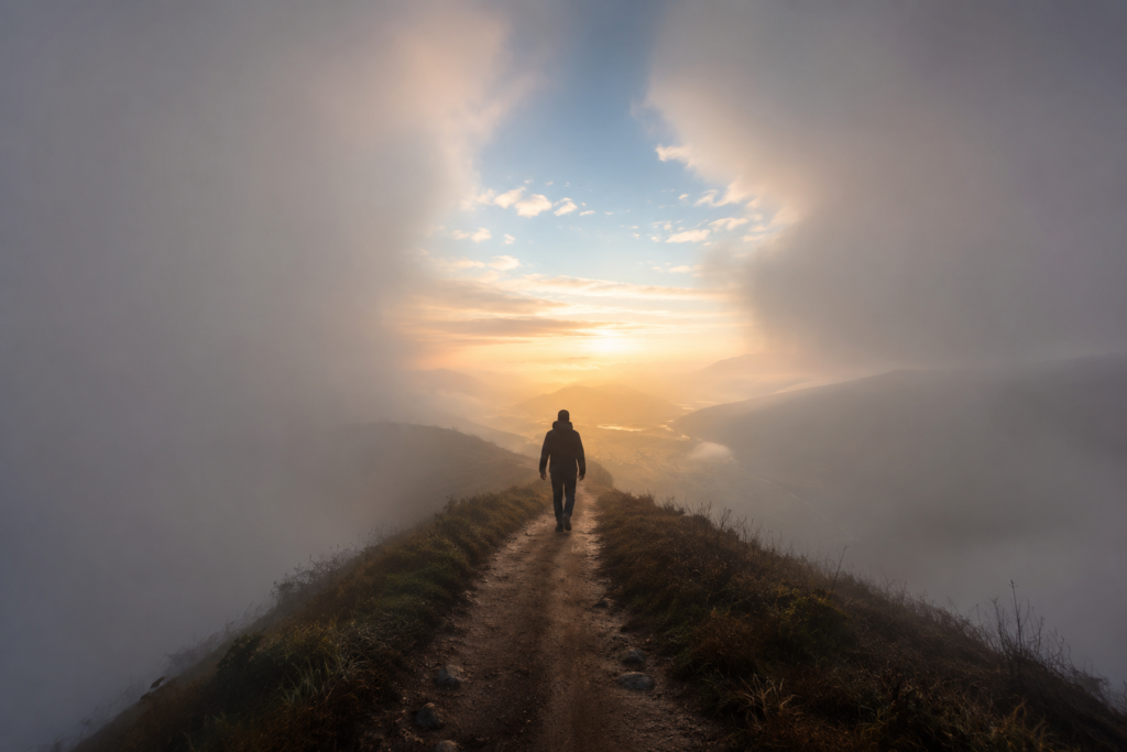 Persona caminando por un camino rodeado de nubes